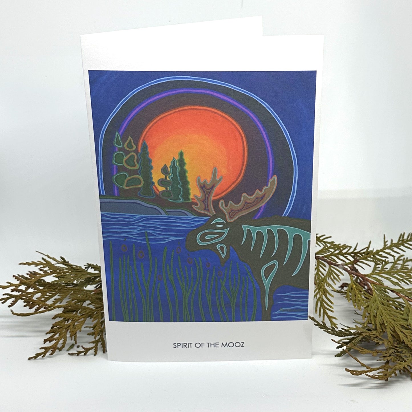 Patrick Hunter's original painting in woodland art style, Spirit of the Mooz, as a greeting card standing open and framed by cedar boughs.